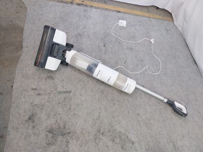 un aspirateur posé par terre à côté d'un lit