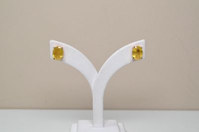 pair of yellow sapphire stud earrings on a white stand