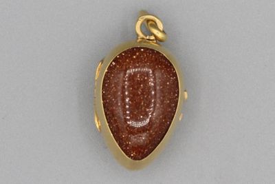 un gros plan d'un pendentif en or orné d'une pierre rouge