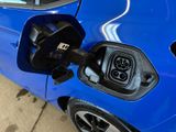 a blue car that has an electric charger attached to it