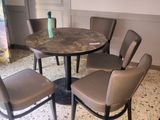 a table and chairs in a room with a painting on the wall