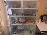 a tall glass cabinet in the corner of a room