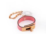 un bracelet en cuir rose muni d'un fermoir doré fixé à une chaîne