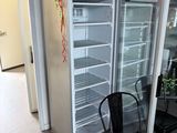 un réfrigérateur avec une porte en verre et une chaise devant
