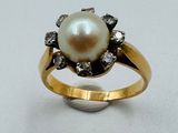 une image d'une bague en perles et diamants sur une surface blanche