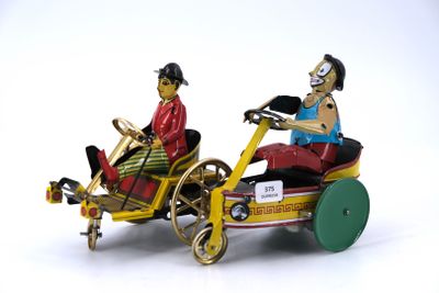 two figurines of a man and a woman riding in a toy car