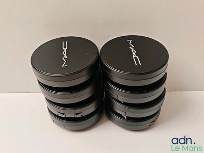 two black and white containers of mac cosmetics sitting on a table