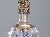 a glass bottle with a gold decoration on the top of it
