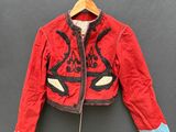 une veste rouge suspendue à un cintre accroché au mur