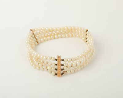 a close up of a bracelet with pearls and a cross on it
