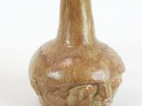 a brown vase with a skull on it on a white surface