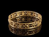 gros plan d'un bracelet en or sur une surface noire