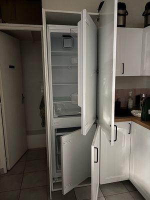 un réfrigérateur ouvert dans une cuisine au sol carrelé