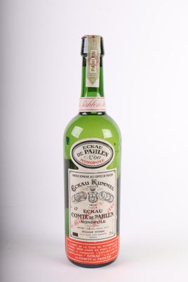an old bottle of liquor sitting on top of a white surface