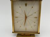 a clock that is sitting on a stand on a white surface