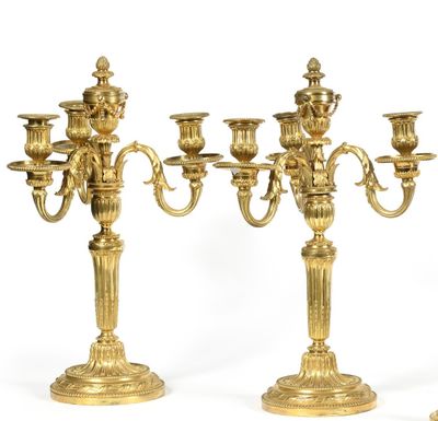 three gold candelabs with candles on a white background