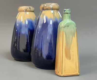three blue and yellow vases sitting next to each other on a gray surface
