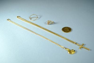 trois colliers en or et une pièce d'or posés sur une surface blanche