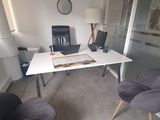a desk with two chairs and a laptop on top of it
