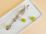 a white plate with grapes and a silver spoon on it