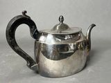 a silver tea pot with a handle on a table