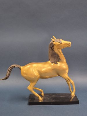 statue d'un cheval jaune sur un socle noir, sur fond bleu