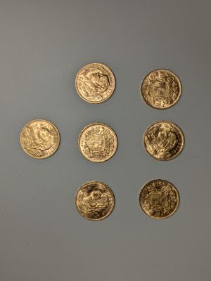 six pièces d'or sont disposées en cercle sur une surface grise