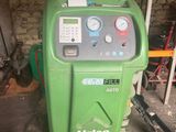 une photo d'une machine verte dans un garage, avec un tuyau d'arrosage