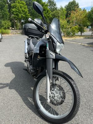 a black motorcycle parked in a parking lot with trees in the background