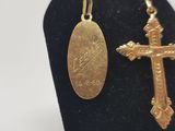 gold plated cross and oval pendant on a black display stand