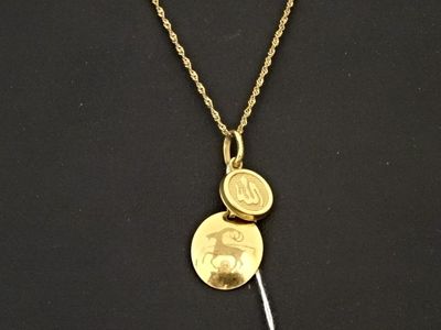 Gros plan sur un collier en or sur lequel se trouve une pièce de monnaie