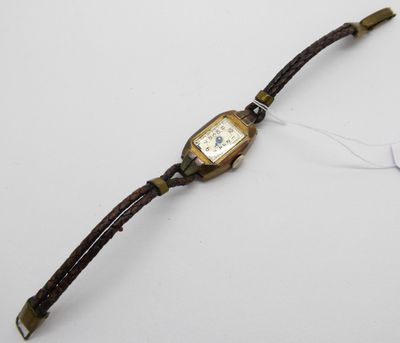 une photo d'une montre-bracelet posée sur une surface blanche, à laquelle est accrochée une étiquette