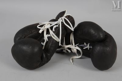 une paire de gants de boxe noirs avec des lacets blancs sur fond gris