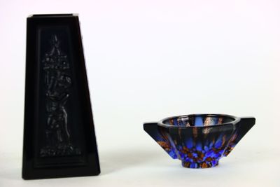un petit bol en verre bleu à côté d'un petit vase noir