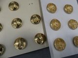 many gold buttons on a sheet of paper next to a sheet of paper