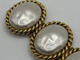 a close up of two white pearls on a gold rope bracelet
