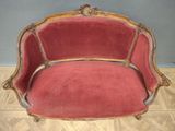 a red couch sitting on a wooden floor in a room