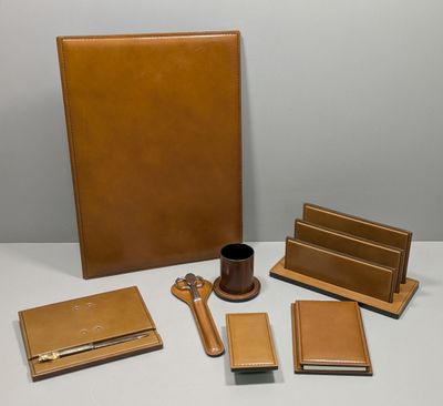 brown leather desk accessories including a pen, notebook, pen holder, and a cup