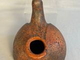 a brown vase with a hole in it on a white surface