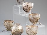 four silver vases sitting on top of clear acrylic stands