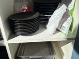 many plates and pans on a shelf in the kitchen