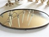 un miroir posé sur une table, dans lequel se reflètent des bougies