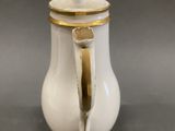 a white and gold coffee pot with a gold handle