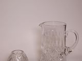 a glass pitcher and a glass bell on a white surface