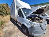 a white van with a broken hood sitting in the dirt