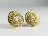 a pair of gold earrings with a circular design