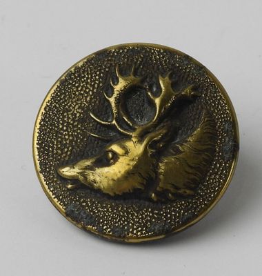 an antique brass button with a deer head and antelope on it