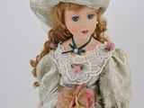 porcelain doll of a woman in a white dress and hat with a cane