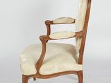 an old fashioned chair with a beige upholstered seat and arms