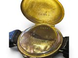 a gold colored pocket watch with a black strap